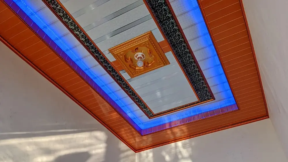 Plafon PVC dengan lis kayu dan lampu LED biru di ruang keluarga