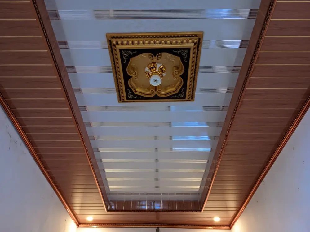 Plafon PVC motif garis dengan ornamen medalion dan lampu hangat